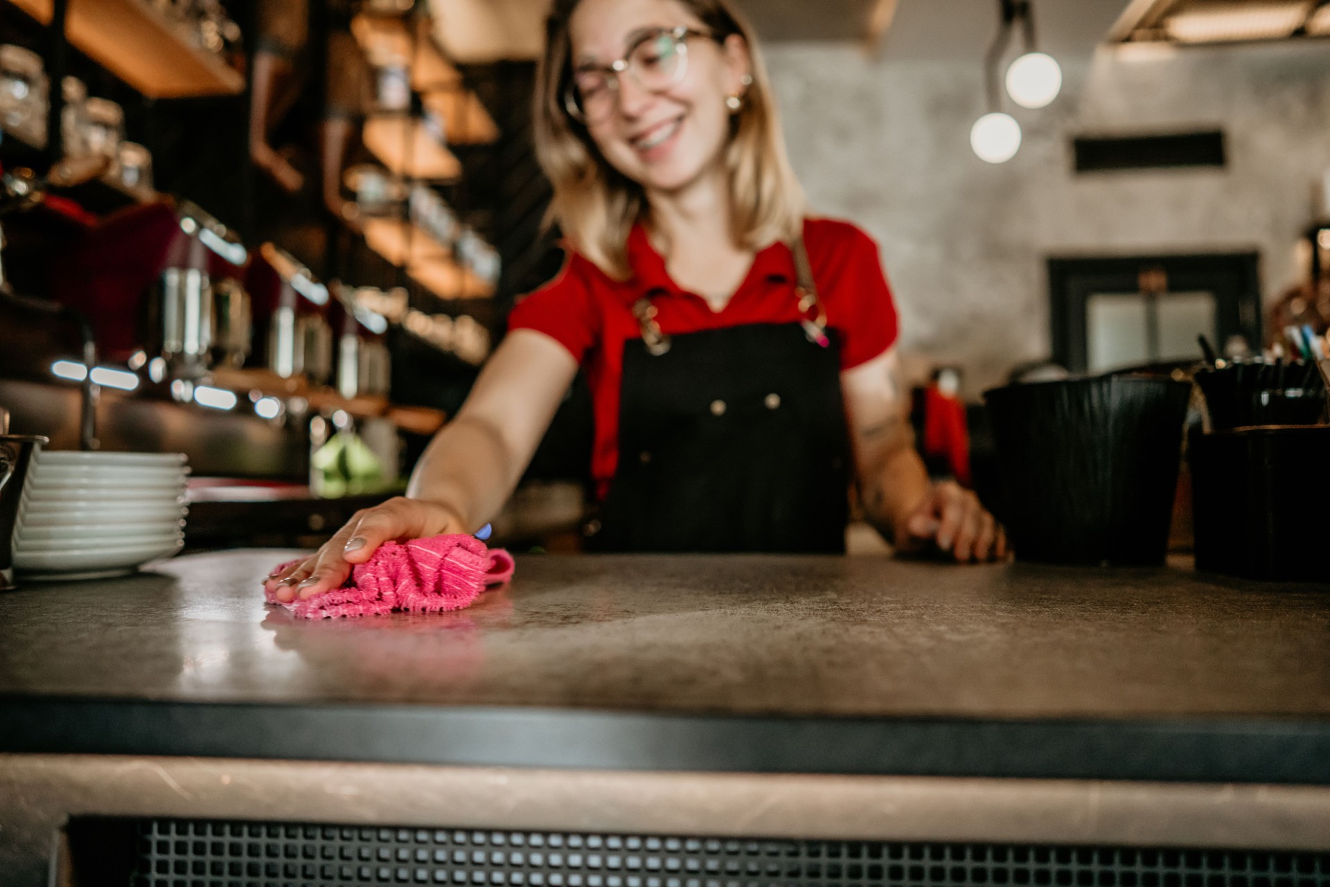 Shot of a young woman disinfecting the tables while working in a restaurant